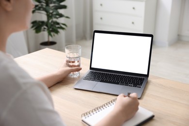 Photo of Woman working with laptop at wooden table indoors, closeup. Mockup for design