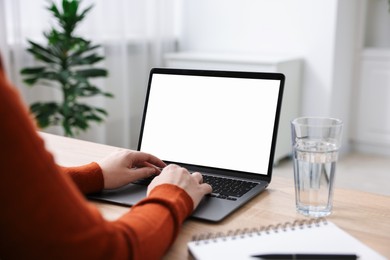 Photo of Woman working with laptop at wooden table indoors, closeup. Mockup for design