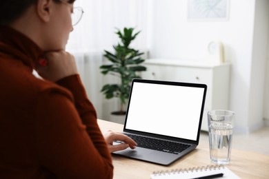 Photo of Woman working with laptop at wooden table indoors, closeup. Mockup for design