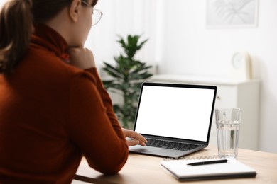 Photo of Woman working with laptop at wooden table indoors, closeup. Mockup for design
