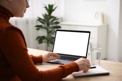 Photo of Woman working with laptop at wooden table indoors, closeup. Mockup for design