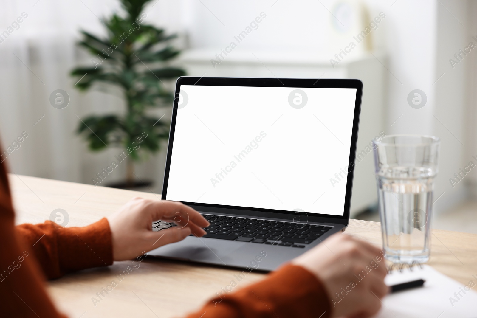 Photo of Woman working with laptop at wooden table indoors, closeup. Mockup for design