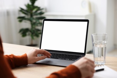 Photo of Woman working with laptop at wooden table indoors, closeup. Mockup for design