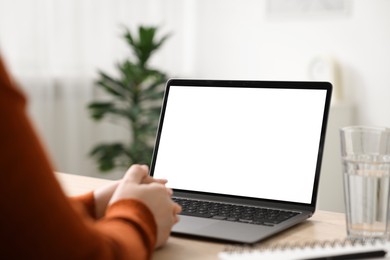 Photo of Woman working with laptop at wooden table indoors, closeup. Mockup for design