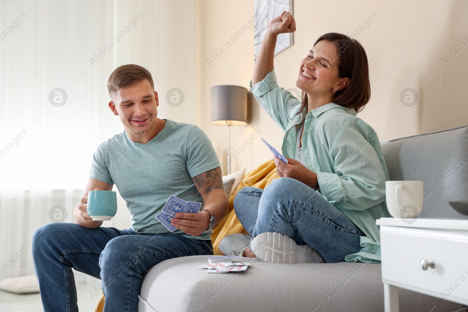 Photo of Man and woman playing cards on sofa at home