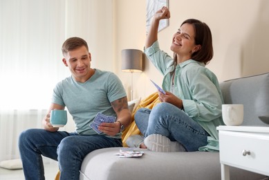 Photo of Man and woman playing cards on sofa at home
