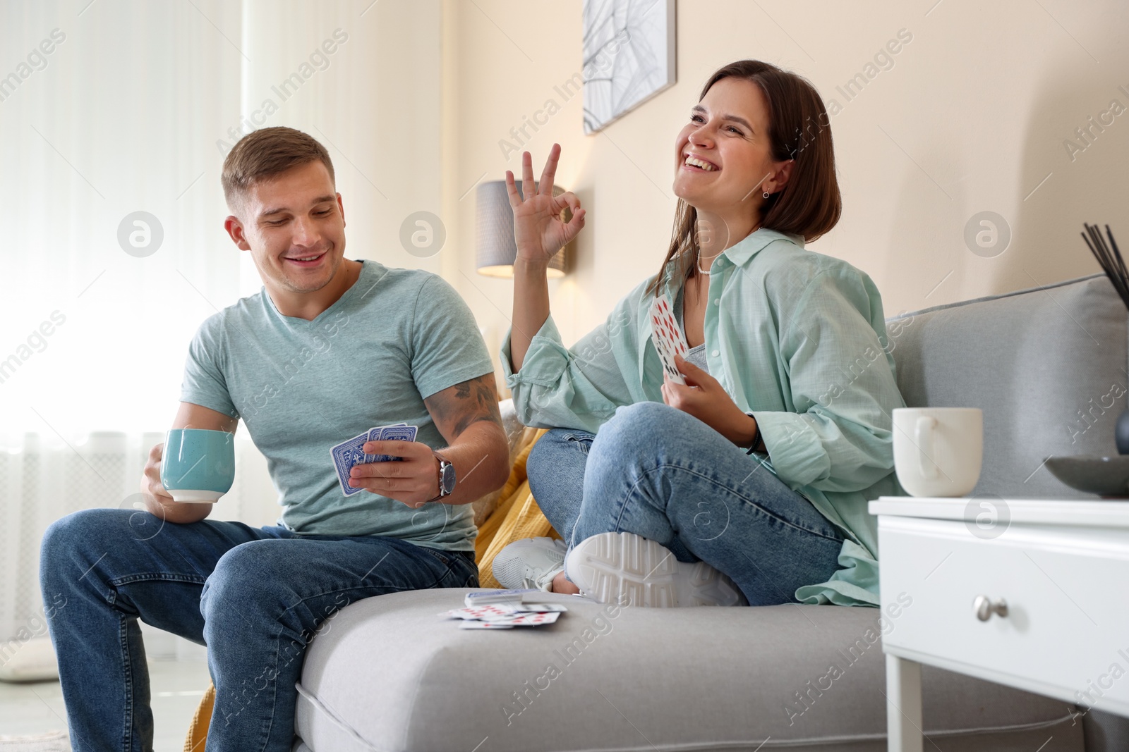 Photo of Man and woman playing cards on sofa at home