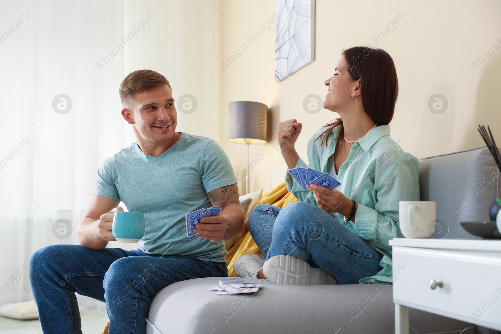 Photo of Man and woman playing cards on sofa at home