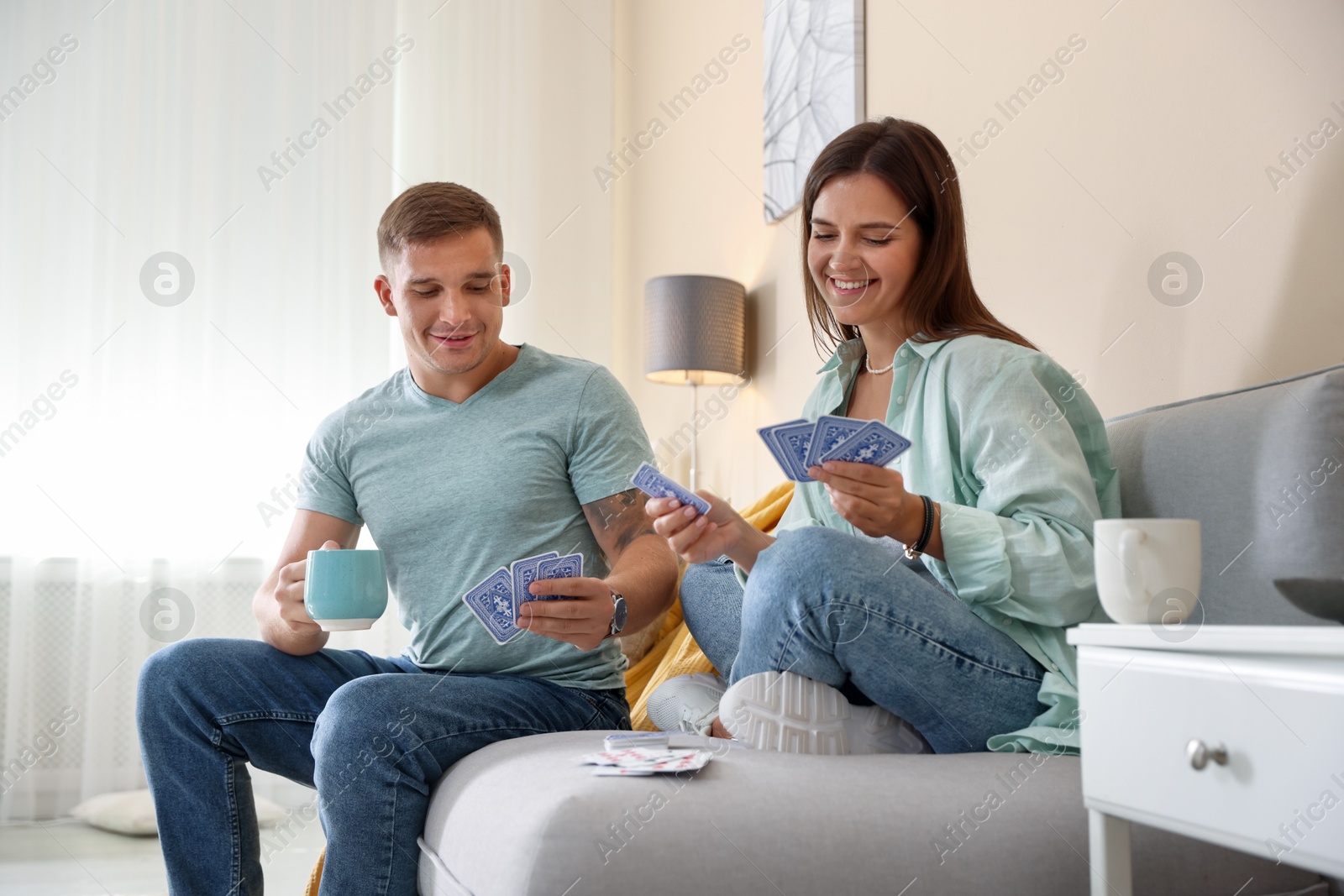 Photo of Man and woman playing cards on sofa at home