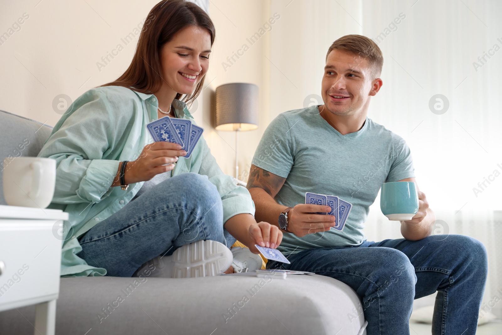 Photo of Man and woman playing cards on sofa at home