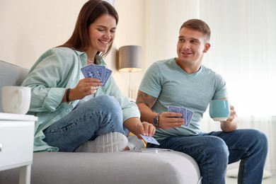 Photo of Man and woman playing cards on sofa at home