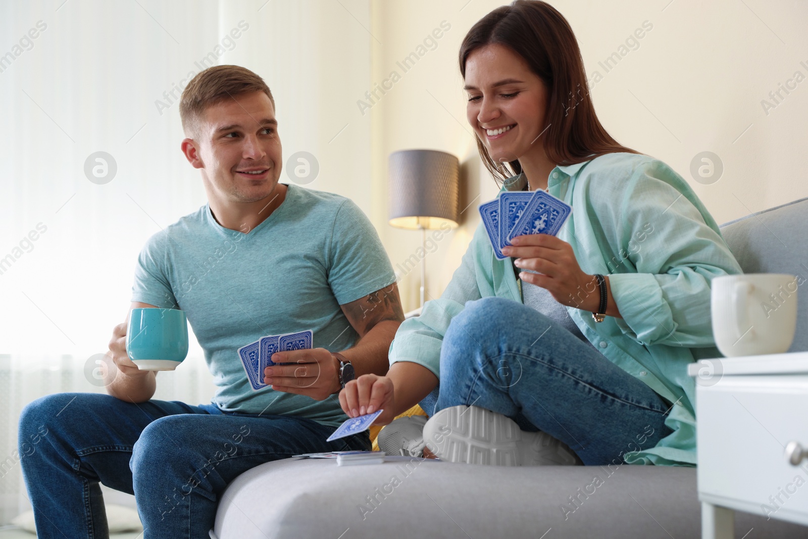 Photo of Man and woman playing cards on sofa at home