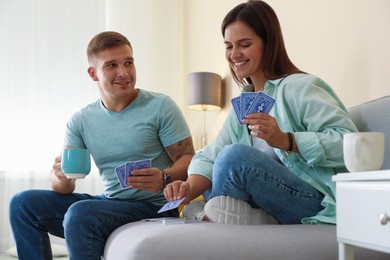 Photo of Man and woman playing cards on sofa at home