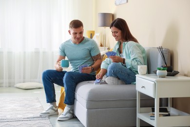 Photo of Man and woman playing cards on sofa at home