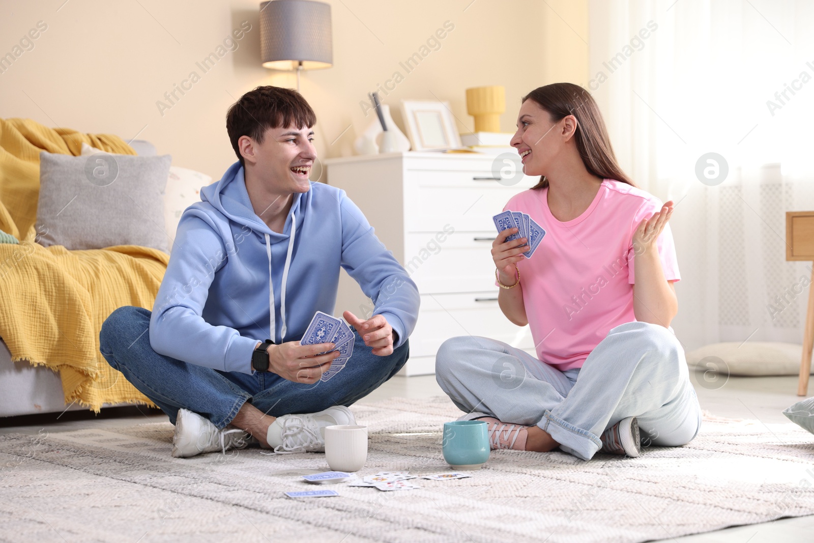 Photo of Man and woman playing cards on floor at home