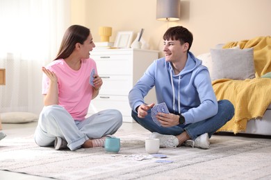 Photo of Man and woman playing cards on floor at home