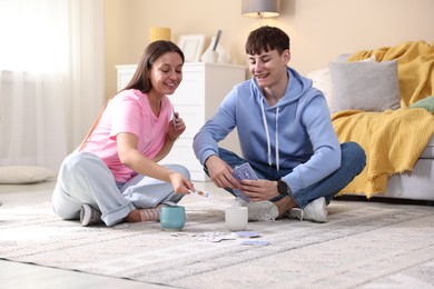 Photo of Man and woman playing cards on floor at home
