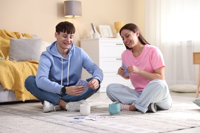 Photo of Man and woman playing cards on floor at home