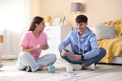 Photo of Man and woman playing cards on floor at home