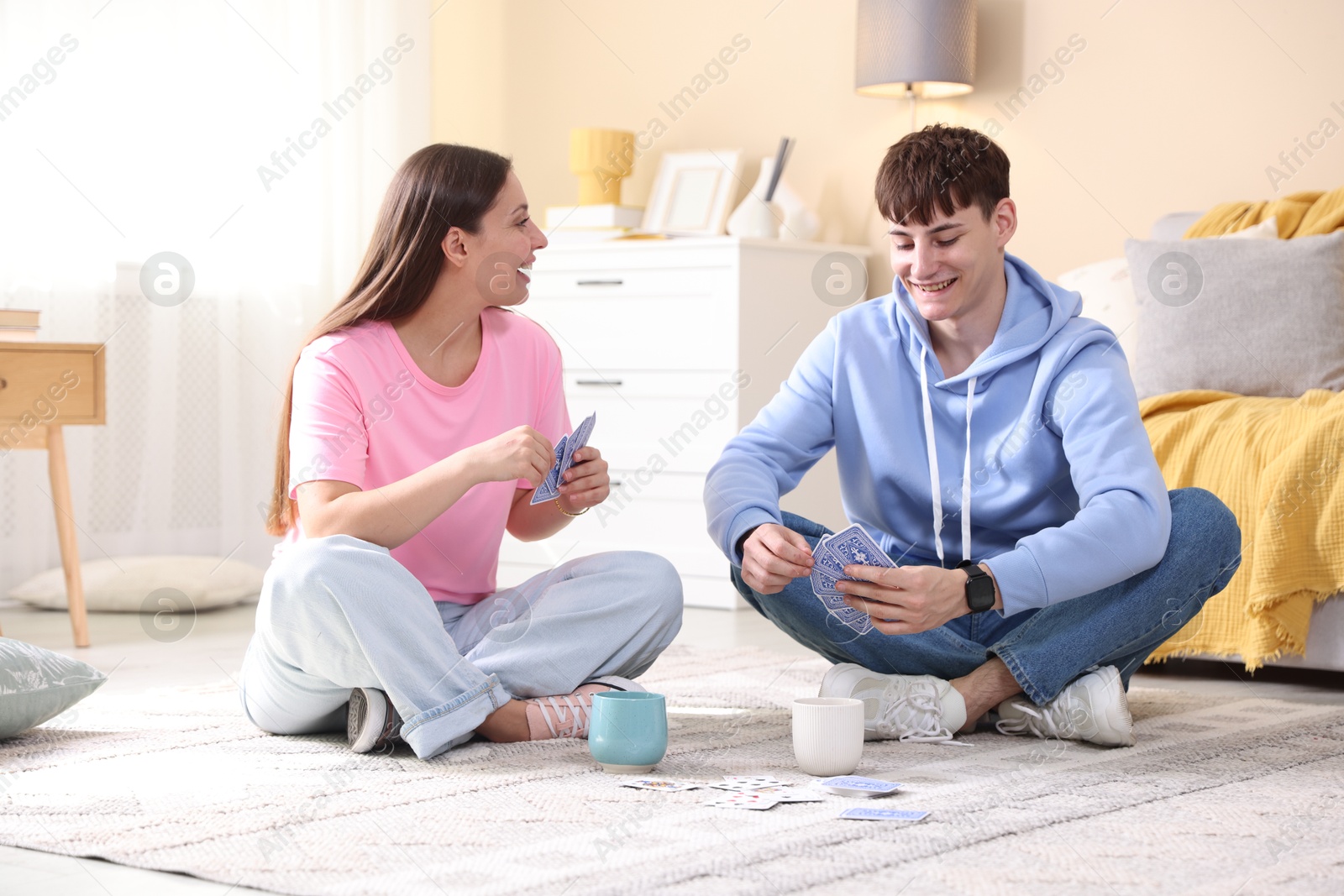 Photo of Man and woman playing cards on floor at home