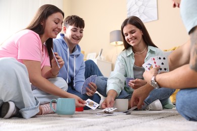Photo of Group of friends playing cards on floor indoors