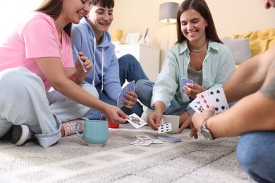 Photo of Group of friends playing cards on floor indoors