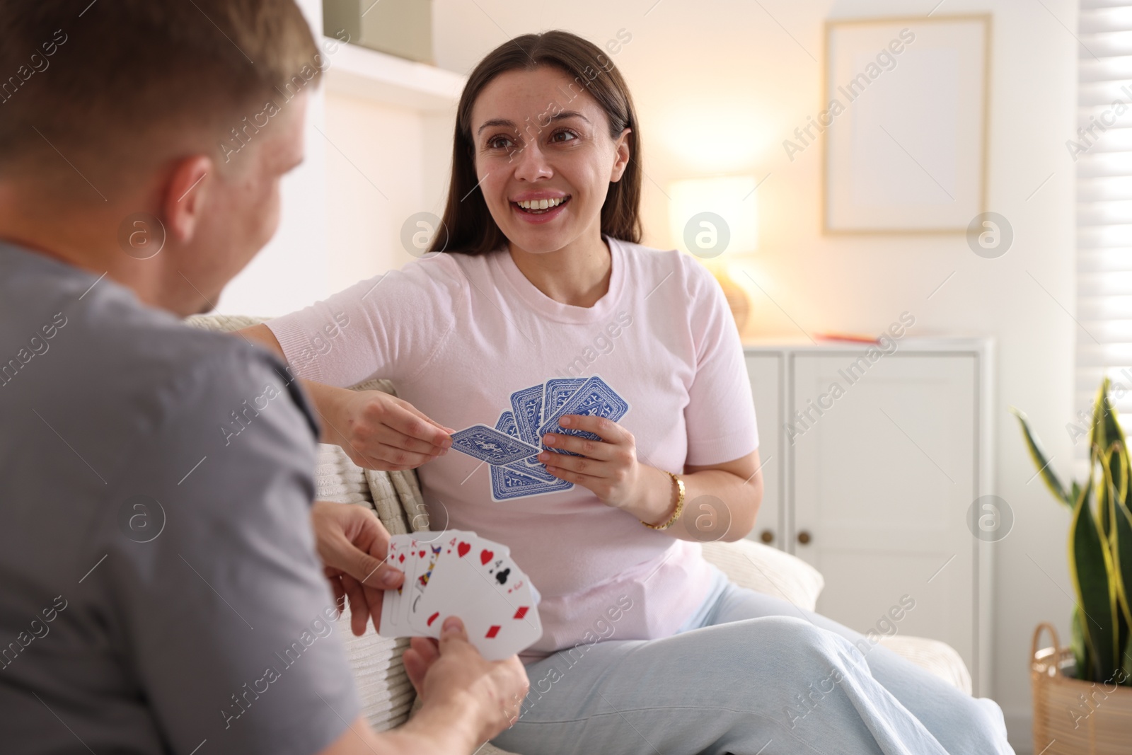 Photo of Man and woman playing cards on sofa at home