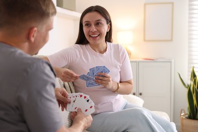 Photo of Man and woman playing cards on sofa at home