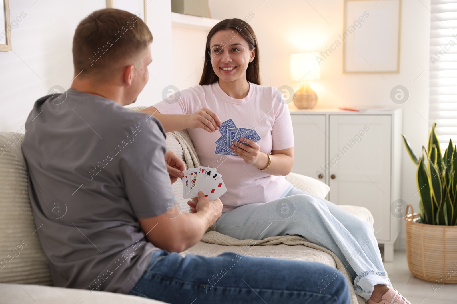 Photo of Man and woman playing cards on sofa at home