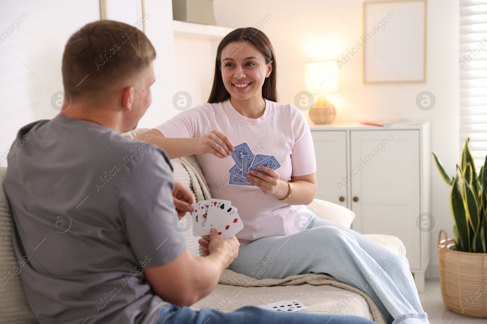 Photo of Man and woman playing cards on sofa at home