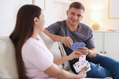 Photo of Man and woman playing cards on sofa at home