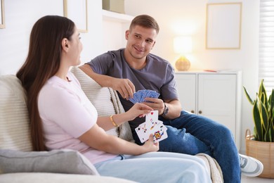Photo of Man and woman playing cards on sofa at home