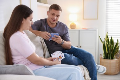 Photo of Man and woman playing cards on sofa at home