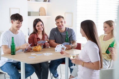 Photo of Group of friends playing cards at wooden table indoors