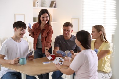 Photo of Group of friends playing cards at wooden table indoors