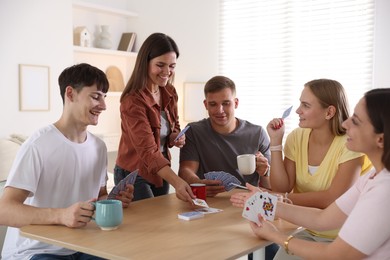 Photo of Group of friends playing cards at wooden table indoors