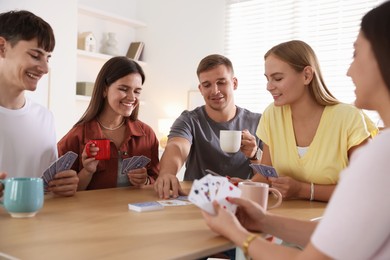 Photo of Group of friends playing cards at wooden table indoors