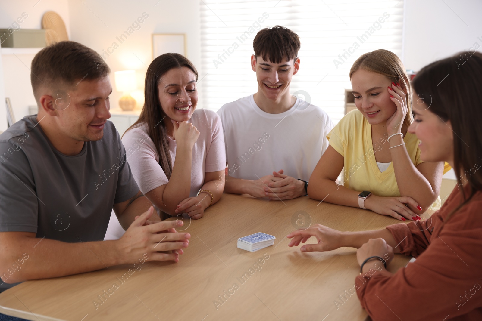 Photo of Group of friends playing cards at wooden table indoors