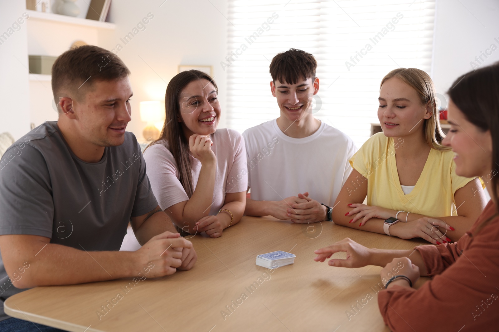 Photo of Group of friends playing cards at wooden table indoors