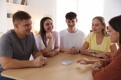 Photo of Group of friends playing cards at wooden table indoors