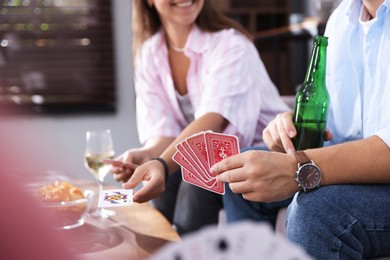 Photo of Friends playing cards at table indoors, selective focus