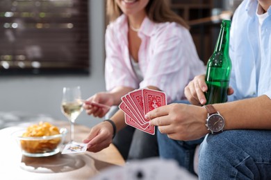 Photo of Friends playing cards at table indoors, selective focus