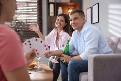 Photo of Friends playing cards at wooden table indoors