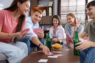 Photo of Group of friends playing cards at wooden table indoors