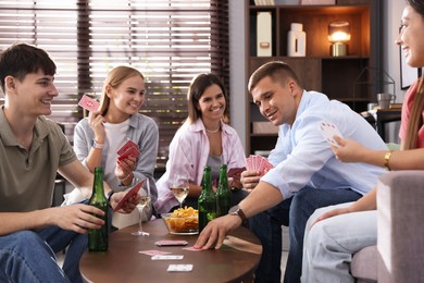 Photo of Group of friends playing cards at wooden table indoors