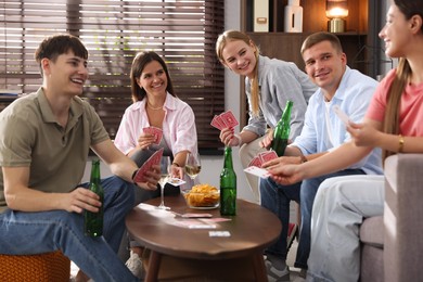 Photo of Group of friends playing cards at wooden table indoors