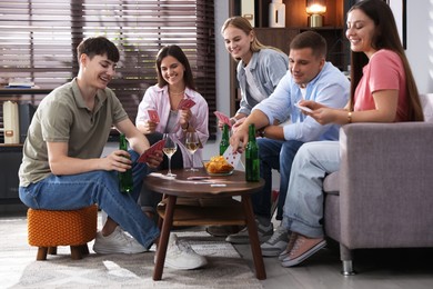 Photo of Group of friends playing cards at wooden table indoors