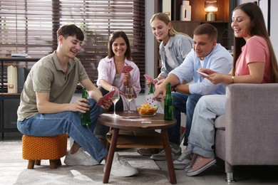 Photo of Group of friends playing cards at wooden table indoors