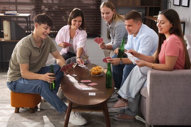Photo of Group of friends playing cards at wooden table indoors