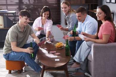 Photo of Group of friends playing cards at wooden table indoors